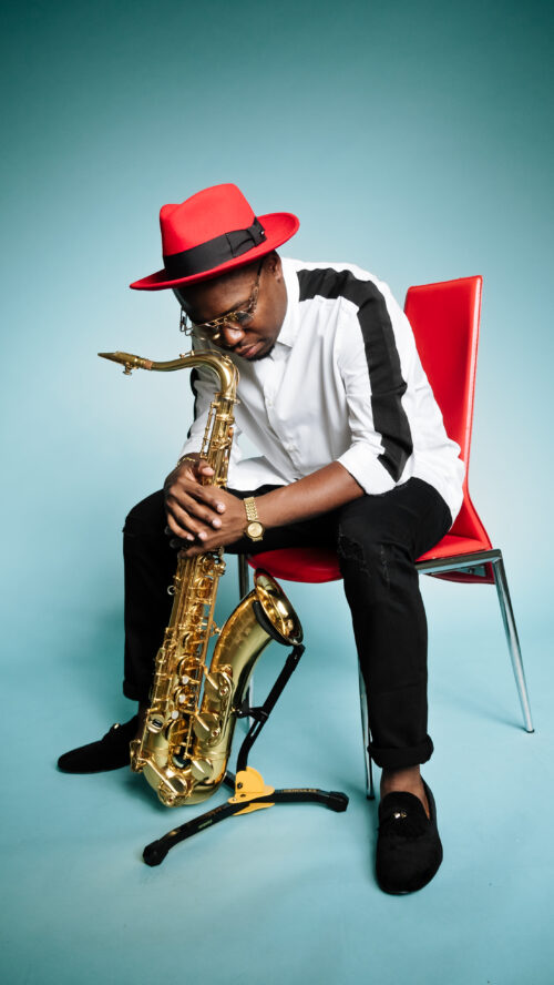 A man sitting on a chair holding a saxophone.