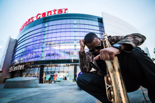 A man sitting on the ground holding a saxophone.