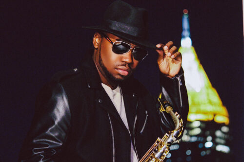 A man in black jacket holding a saxophone.